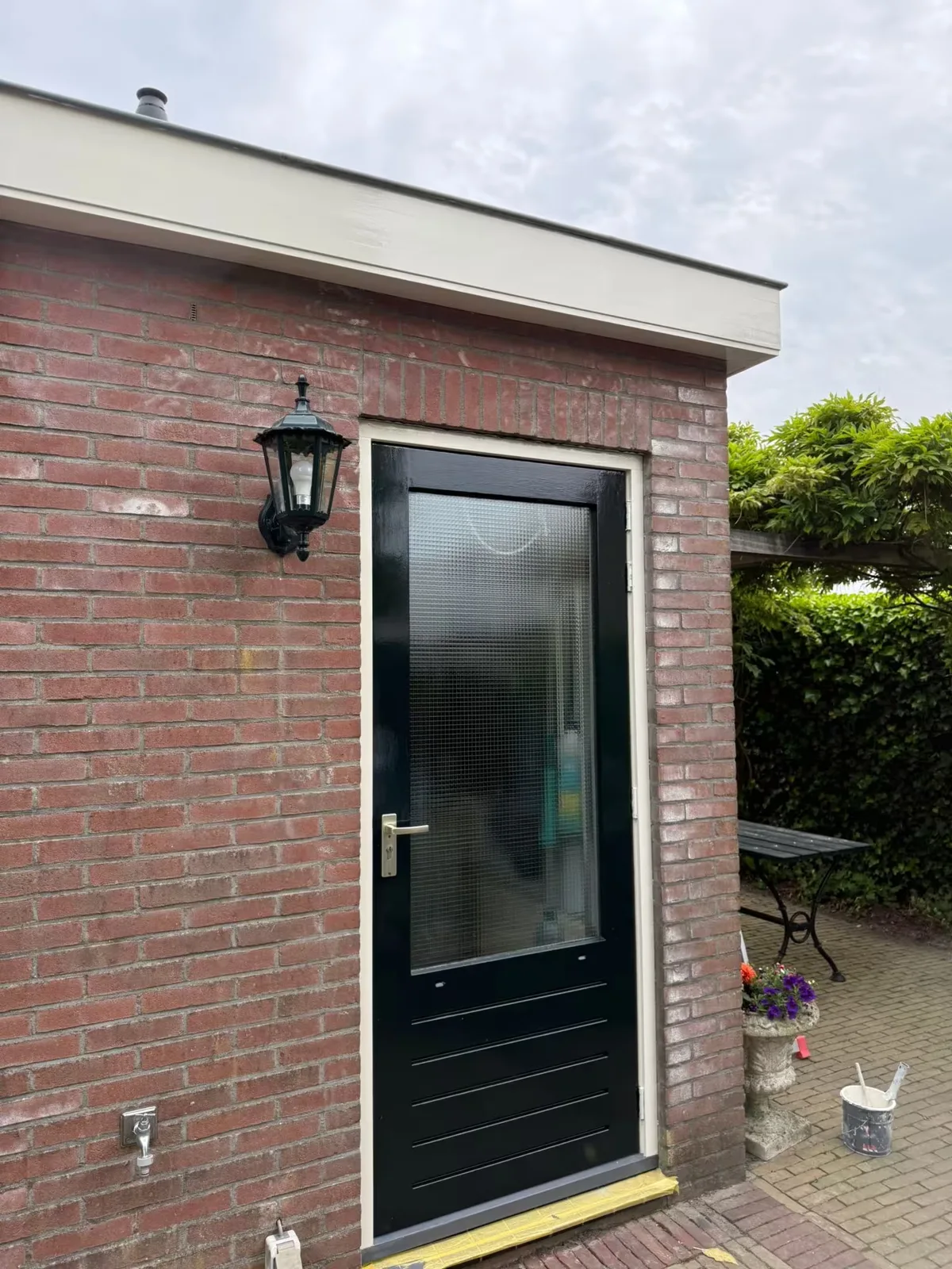 Donkere buitendeur met wit kozijn en licht boeideel bij een MJA-project