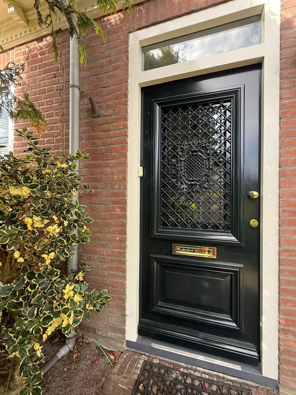 Donkere voordeur met bovenlicht en sierrooster uit het MJA-portfolio