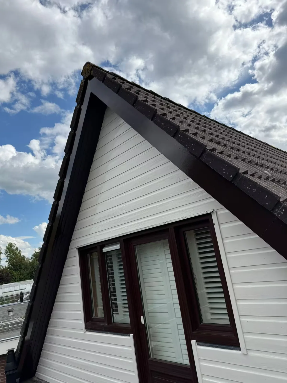 Dezelfde houten gevelbekleding na de afwerking in wit en donker houtwerk