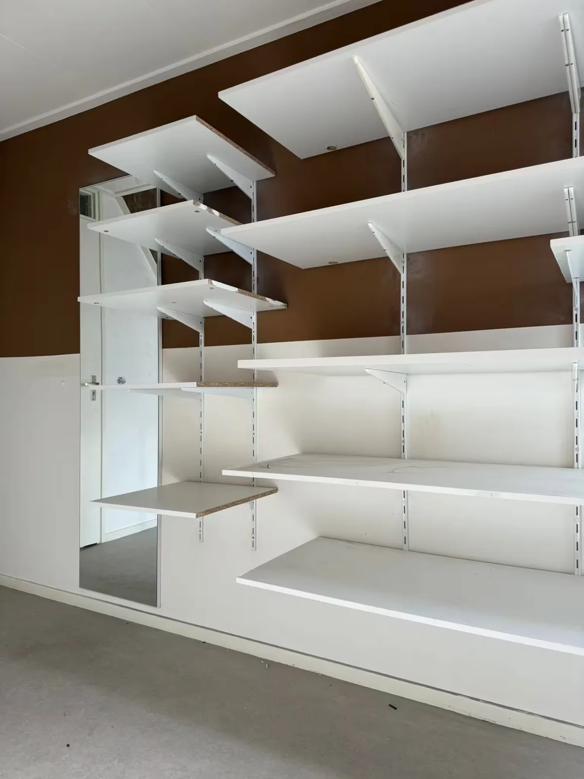 Witte open kast met planken tijdens de afwerking door MJA